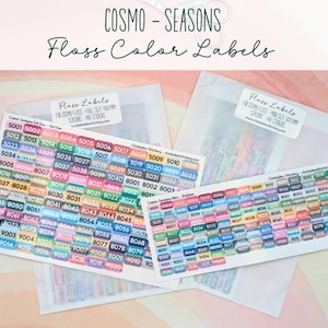May include: A collection of floss color labels with the text "COSMO - SEASONS Floss Color Labels." The labels are organized by color and number, with a variety of colors and numbers visible. The labels are in clear plastic sleeves.