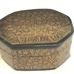 May include: An octagonal decorative box with a black base and lid. The lid and sides are adorned with a gold leaf pattern of a tree and foliage. The box has a green trim around the lid.