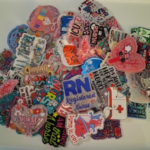 May include: A collection of colorful, glittery nurse-themed badge reels and pins. Designs include hearts, medical symbols, and text such as "Nurse", "ICU", and "Registered Nurse". The pins feature various colors and styles.