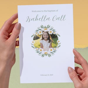 May include: A baptism announcement featuring the text "Welcome to the baptism of Isabella Call" in elegant script. The announcement includes a photo of a smiling girl framed by a floral wreath and the date February 8, 2025.