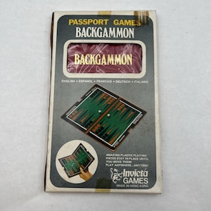 May include: A vintage Passport Games Backgammon set in its original box. The box is gray and white with the game's name in gold lettering. The game board is green and brown, with red and white game pieces. The box also includes the text "Invicta Games Made in Hong Kong."