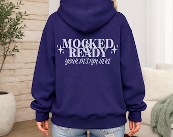 Puede incluir: Una sudadera con capucha azul marino con el texto "MOCKED & READY your DESIGN HERE" en blanco. La sudadera tiene una capucha con cordón y un bolsillo de canguro. El modelo lleva vaqueros azules.