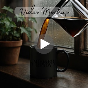 May include: A black coffee mug with the text "MOCKED + READY" is being filled with dark coffee from a glass carafe. The scene is set on a wooden windowsill with a potted plant in the background. The image has a video mockup overlay.