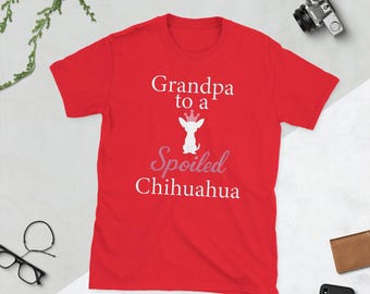 Op de afbeelding: Een rood t-shirt met de tekst "Grandpa to a Spoiled Chihuahua" in wit en roze. Het ontwerp bevat een Chihuahua met een kroon. Het shirt heeft korte mouwen en is gemaakt van een zacht materiaal.