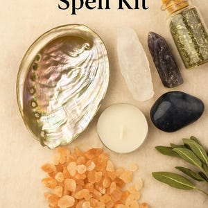 Può includere: Un kit di incantesimi di magia glamour con vari elementi. Include una conchiglia di abalone iridescente, cristalli, una candela, un piccolo barattolo con un tappo, una pietra blu scuro, sale rosa-arancio e foglie di salvia. Disposto su una superficie beige chiaro.