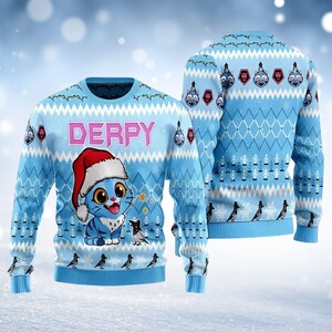 May include: Light blue Christmas jumper featuring a cartoon cat wearing a Santa hat, with the word "DERPY" above. The jumper has a repeating pattern of diamonds, snowflakes, and birds. The back of the jumper has a similar design.