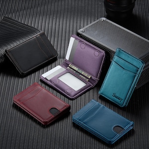 May include: A collection of leather cardholders in various colors, including black, burgundy, teal, and blue. One cardholder is open, revealing card slots and a clear ID window. The teal cardholder has the word "Sunny" embossed on it.