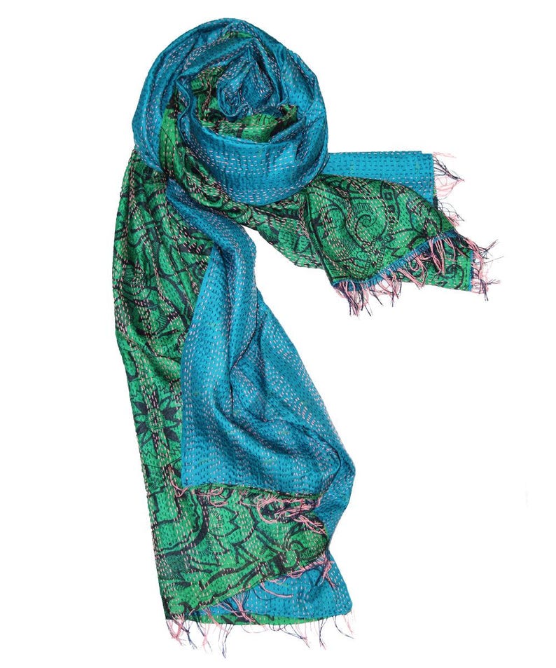 May include: A vibrant, handmade scarf in shades of teal and green. The scarf features intricate stitching and a detailed pattern, with a fringed edge. The design incorporates both solid and patterned sections, creating a visually appealing accessory.