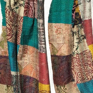 May include: A patchwork textile featuring a variety of colors and patterns. The design incorporates rectangular patches of teal, burgundy, yellow, and cream fabrics. The textile has a vintage, handcrafted appearance, with visible stitching.