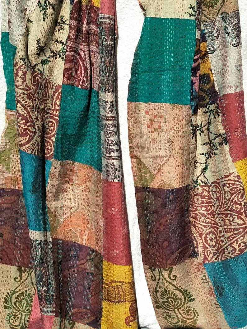 May include: A patchwork textile featuring a variety of colors and patterns. The design incorporates rectangular patches of teal, burgundy, yellow, and cream fabrics. The textile has a vintage, handcrafted appearance, with visible stitching.