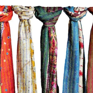 May include: Five colorful scarves hanging against a white background. The scarves display a variety of patterns and colors, including red, orange, blue, green, and yellow. Each scarf is unique, with different designs and textures.