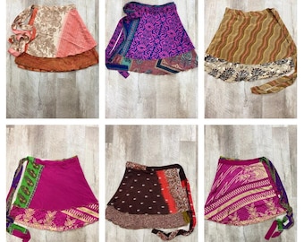 Pode incluir: Coleção de seis saias envelope coloridas. Cada saia apresenta padrões e designs únicos, incluindo motivos florais, geométricos e paisley. As saias exibem uma variedade de cores, como rosa, roxo, marrom e verde, com bordas e laços contrastantes.