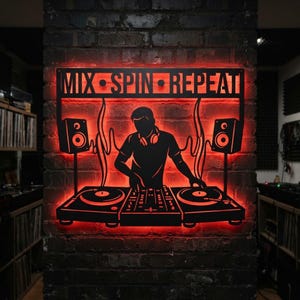 May include: A black metal wall art piece featuring a silhouette of a DJ at a mixing console with two speakers and the text MIX SPIN REPEAT. The design is backlit with a vibrant red glow, highlighting the cut-out details against the dark brick wall.