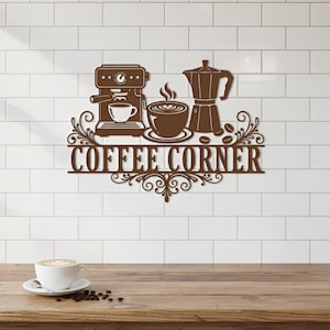 May include: A brown metal wall art piece with the words "COFFEE CORNER" and coffee-related imagery. The design includes an espresso machine, a cup of coffee, a coffee pot, and coffee beans. The art is mounted on a white tiled wall.