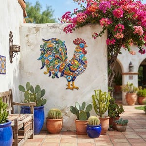 May include: A decorative wall-mounted rooster sculpture featuring a vibrant, multi-colored Talavera-style pattern with intricate floral and geometric motifs in shades of blue, yellow, orange, green, and red, displayed on a white wall.