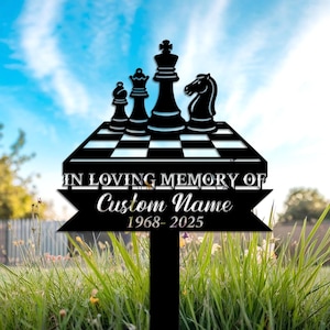 May include: Black metal memorial garden stake featuring a chess board with chess pieces. The stake includes the text "IN LOVING MEMORY OF" above a banner with "Custom Name" and the years "1968-2025". The background is a blue sky and green grass.