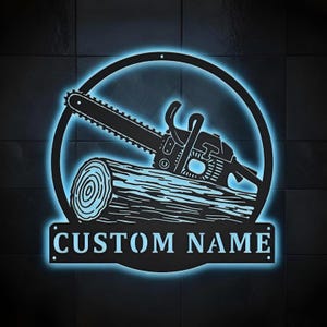 Pode incluir: Design em metal preto de motosserra e tronco com brilho néon azul. A motosserra repousa sobre um tronco dentro de uma moldura circular. As palavras "CUSTOM NAME" são exibidas em uma faixa retangular.