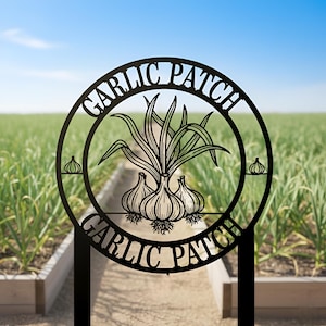 May include: Black metal garden sign with the words "GARLIC PATCH" in a circular design. The center features a garlic plant illustration. The sign is placed in a garden with a blue sky background.