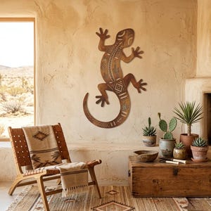 May include: A large, brown metal lizard wall art piece with intricate tribal patterns. The lizard is mounted on a textured, light-colored wall. The image also shows a wooden chair, a rug, and potted plants, creating a Southwestern theme.