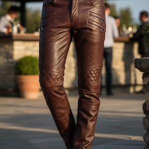 Può includere: Pantaloni in pelle marrone con pannelli trapuntati sulle ginocchia e tasche con cerniera. I pantaloni hanno un classico design a cinque tasche e una chiusura con bottone e cerniera. La pelle ha una leggera lucentezza.