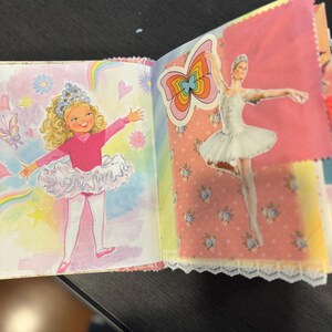 Pu&ograve; includere: Un diario fatto a mano con pagine con illustrazioni di ballerine e farfalle. Una pagina ha un disegno di una ballerina in un body e tut&ugrave; rosa. Un'altra pagina ha un adesivo di una ballerina in un tut&ugrave; bianco.