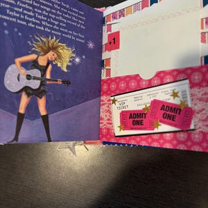Pu&ograve; includere: Una pagina di scrapbook a tema concerto. Il lato sinistro presenta testo e un'illustrazione di una cantante con una chitarra. Il lato destro ha una tasca con due biglietti rosa "Admit One" e un biglietto VIP.