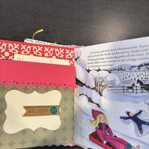 Pu&ograve; includere: Diario aperto con copertina fantasia rossa e bianca, con tasca rosa con bordo decorativo. La pagina sinistra ha un'etichetta decorativa con la parola "BELIEVE". La pagina destra mostra una scena invernale con bambini che vanno in slitta.