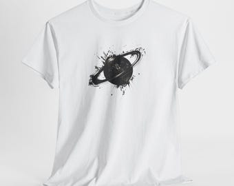 May include: White t-shirt featuring a black graphic of a planet with a ring, surrounded by paint splatter. The design is centered on the front of the shirt. The shirt has short sleeves and a crew neck.