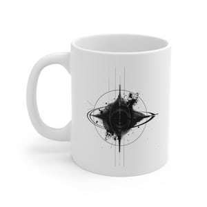 Puede incluir: Taza de café de cerámica blanca con un diseño abstracto en blanco y negro. El diseño incluye una forma central de estrella con un contorno circular y efectos de salpicaduras de tinta. La taza tiene un asa curva.