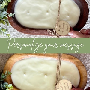 May include: A large, oval candle in a wooden bowl. The cream-coloured candle has multiple wicks. A twine bow holds a wooden tag that reads "Happy Birthday Megan!" The text "Personalize your message" is also visible.