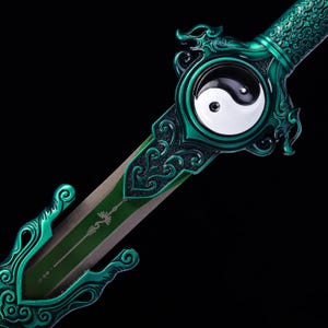 Könnte beinhalten: Ein Schwert mit einem metallisch smaragdgrünen Griff und Parierstange mit komplizierten Schnörkelmustern. In der Mitte der Parierstange befindet sich ein kreisförmiges schwarz-weißes Yin-Yang-Symbol. Die Klinge ist teilweise mit einem grünen Mittelstreifen sichtbar.