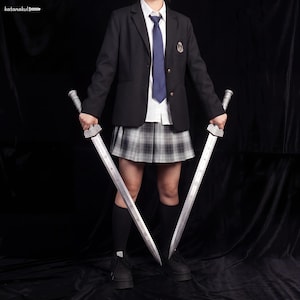 May include: Two silver swords with ornate handles are held in front of a person wearing a black blazer, white shirt, plaid skirt, and black shoes. The swords have long, straight blades and detailed grips. The person is standing against a black backdrop.