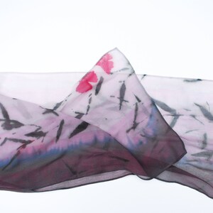 May include: A sheer pink scarf with a black and white abstract design and pink floral accents.
