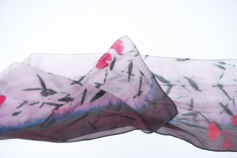 May include: A sheer pink scarf with a black and white abstract design and pink floral accents.