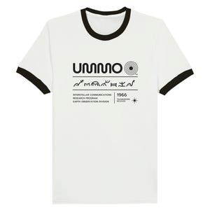 May include: A white ringer t-shirt with black trim on the collar and sleeves. The chest features a black graphic with the text UMMO, a circular symbol, a row of abstract glyphs, and the text INTERSTELLAR COMMUNICATIONS RESEARCH PROGRAM 1966.