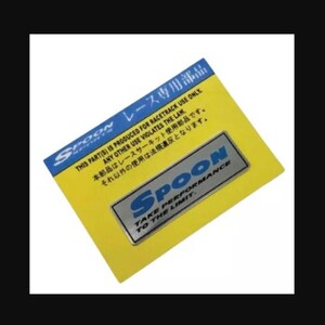 Puede incluir: Un emblema Spoon plateado y azul sobre un fondo amarillo. El emblema tiene la palabra "SPOON" y el texto "TAKE PERFORMANCE TO THE LIMIT". El texto en japonés e inglés indica que la pieza es solo para uso en circuito.