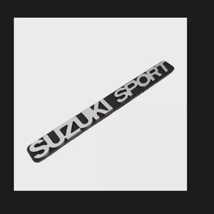 May include: A black and silver Suzuki Sport emblem. The emblem is rectangular and features the words "SUZUKI SPORT" in silver lettering. The background is black.