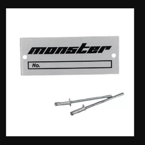Puede incluir: Una placa rectangular plateada con la palabra "monster" en negro en negrita. Debajo, una caja rectangular con la palabra "No." encima. Dos remaches plateados debajo.