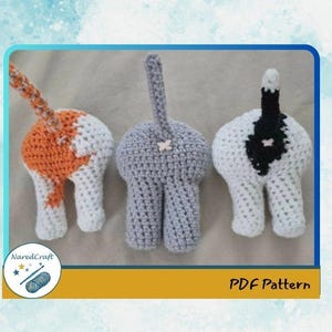 Puede incluir: Tres adornos hechos a mano de crochet con forma de trasero de gato en blanco, naranja, gris y negro. Los adornos tienen colas y se muestran sobre un fondo neutro. La imagen incluye el texto "PDF Pattern" y un logotipo.