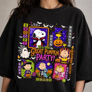 Op de afbeelding: Een zwart t-shirt met een kleurrijke Halloween-afbeelding met Snoopy, Charlie Brown, Lucy, Linus, Sally en Woodstock. Het ontwerp bevat de tekst 'It's the GREAT PUMPKIN PARTY!', omringd door pompoenen, spoken, vleermuizen en spinnenwebben.