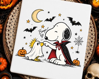 May include: A white square tile featuring a cartoon illustration of Snoopy dressed as a vampire touching the nose of Woodstock dressed as a ghost. The design includes a yellow crescent moon, black bats, orange pumpkins, a spider web, and the text Boop!