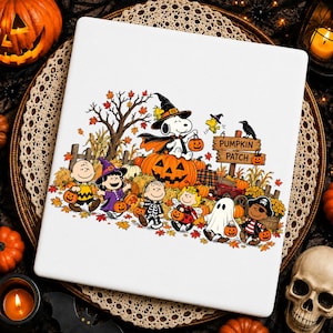 May include: A white square sign featuring a colorful Peanuts Halloween illustration. Snoopy wears a witch hat and cape atop a large jack-o'-lantern. Charlie Brown and friends are in costumes including a ghost, pirate, and ladybug near a pumpkin patch.