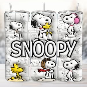May include: A cylindrical tumbler with a straw featuring a black and white comic strip background of Snoopy and Woodstock. The word SNOOPY is printed in large white letters across the centre. Various illustrations of Snoopy are shown in different outfits, including a pilot cap and pink earmuffs, alongside the yellow bird Woodstock.