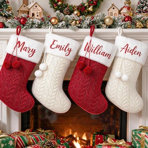 May include: Four Christmas stockings hanging in a row, alternating between deep red and cream white cable knit textures. Each stocking features a plush white cuff embroidered with the names Mary, Emily, William, and Aiden in red script.