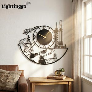 May include: Black metal wall clock with a space theme, featuring a clock face, rocket, planets, and a shuttle. The clock has gold-colored hands and the text "Lightinggo Studio" in the upper left corner.