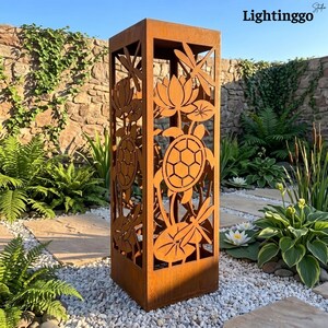 May include: A tall, rectangular, rust-coloured metal garden sculpture featuring laser-cut designs of turtles, dragonflies, and lotus flowers on its sides. The structure has an open frame design and a weathered, oxidised finish.
