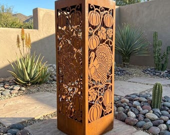 May include: A tall, rectangular, rust-colored metal garden sculpture featuring laser-cut designs of turkeys, pumpkins, and foliage. The structure has an openwork pattern and the text Lightinggo is visible in the upper right corner.