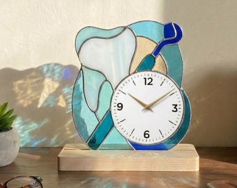 May include: A stained glass clock shaped like a tooth and dental tool. The clock face is white with black numerals and gold hands. The clock sits on a wooden base. The image has the text "Lightinggo".