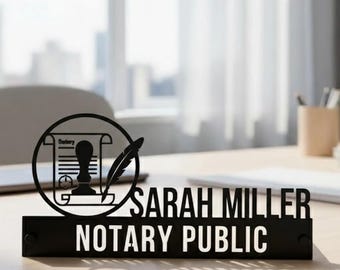May include: Black desk nameplate with the text "SARAH MILLER NOTARY PUBLIC" in white lettering. A circular design with a quill and a notary stamp is above the name. The nameplate is on a light-coloured desk.