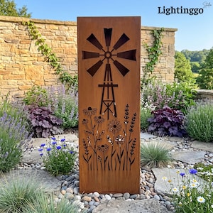 May include: A tall, rectangular, rust-colored metal garden screen featuring a laser-cut design of a windmill at the top and a field of various wildflowers at the bottom. The panel has a weathered, oxidized finish and stands upright.